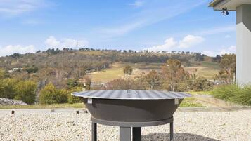 A barbecue grill with a view of a hilly landscape.