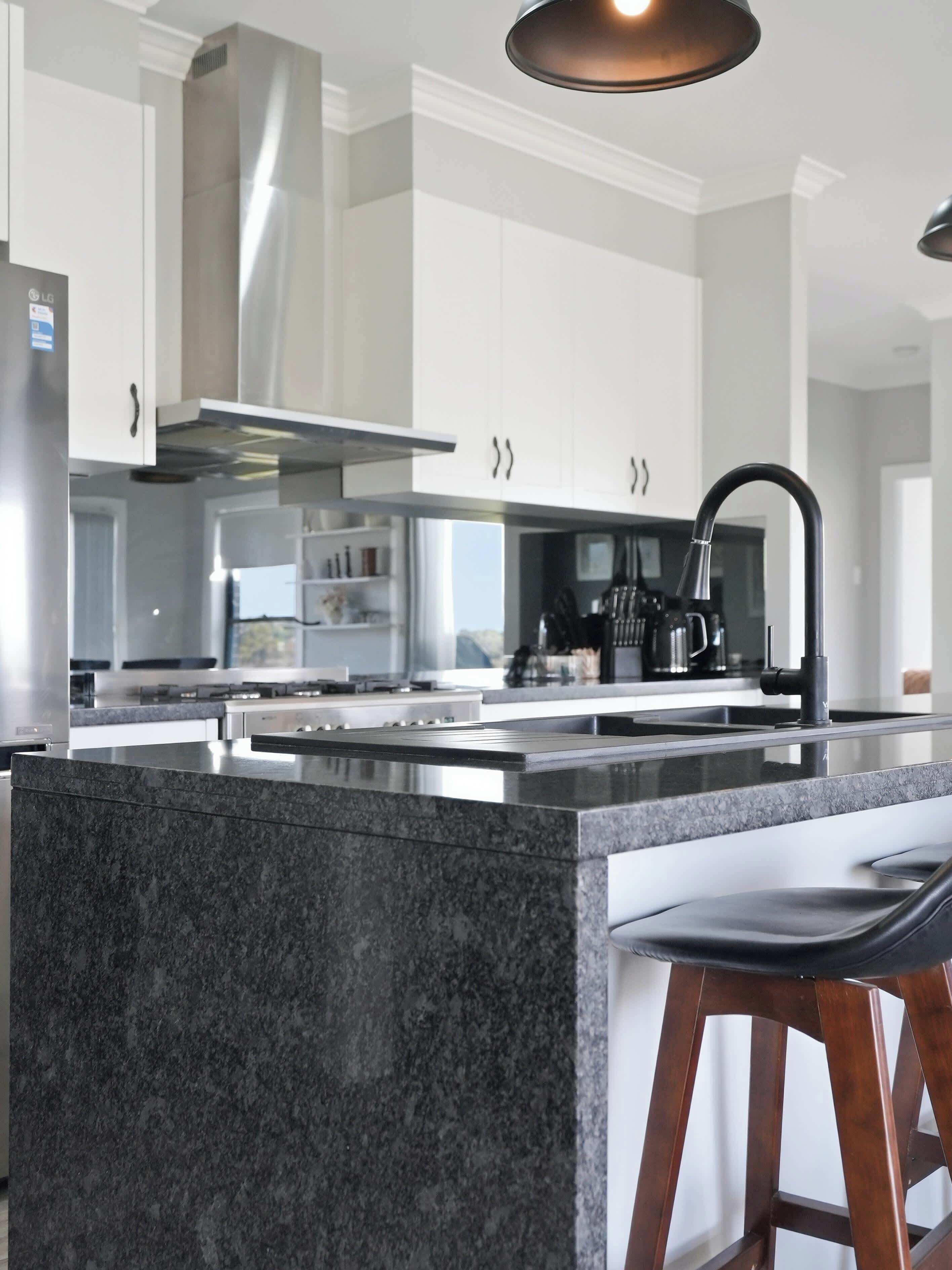 Una cocina moderna con una isla central, electrodomésticos de acero inoxidable y una lámpara colgante.