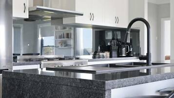 Una cocina moderna con una isla central, electrodomésticos de acero inoxidable y una lámpara colgante.