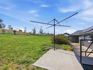 A grassy outdoor area with a concrete pathway leading to a building with a metal staircase. - Boundary Retreat, Bathurst Views & Firepit (Evans Plains)