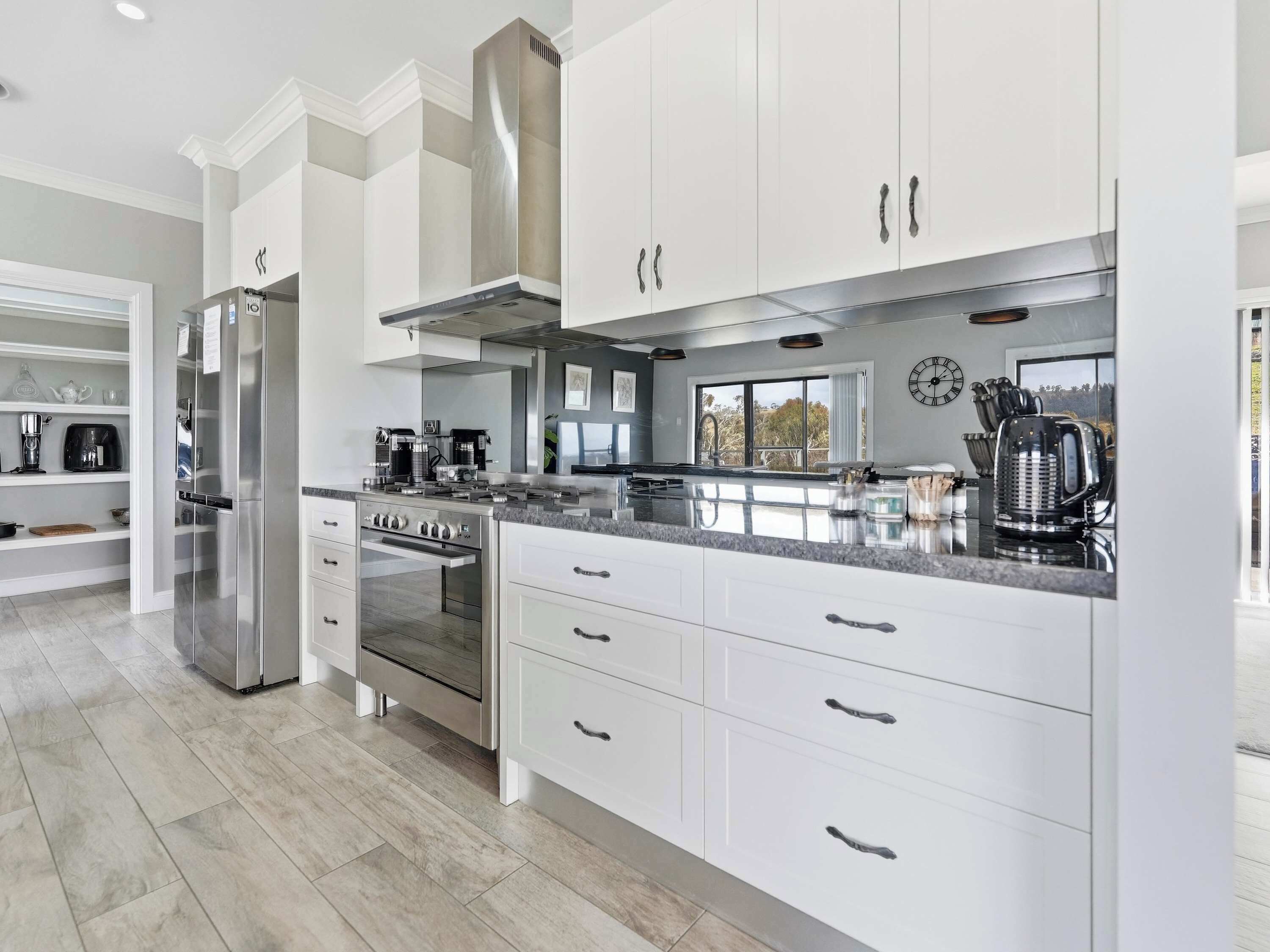 A modern kitchen with white cabinetry, stainless steel appliances, and a large island with a built-in oven.