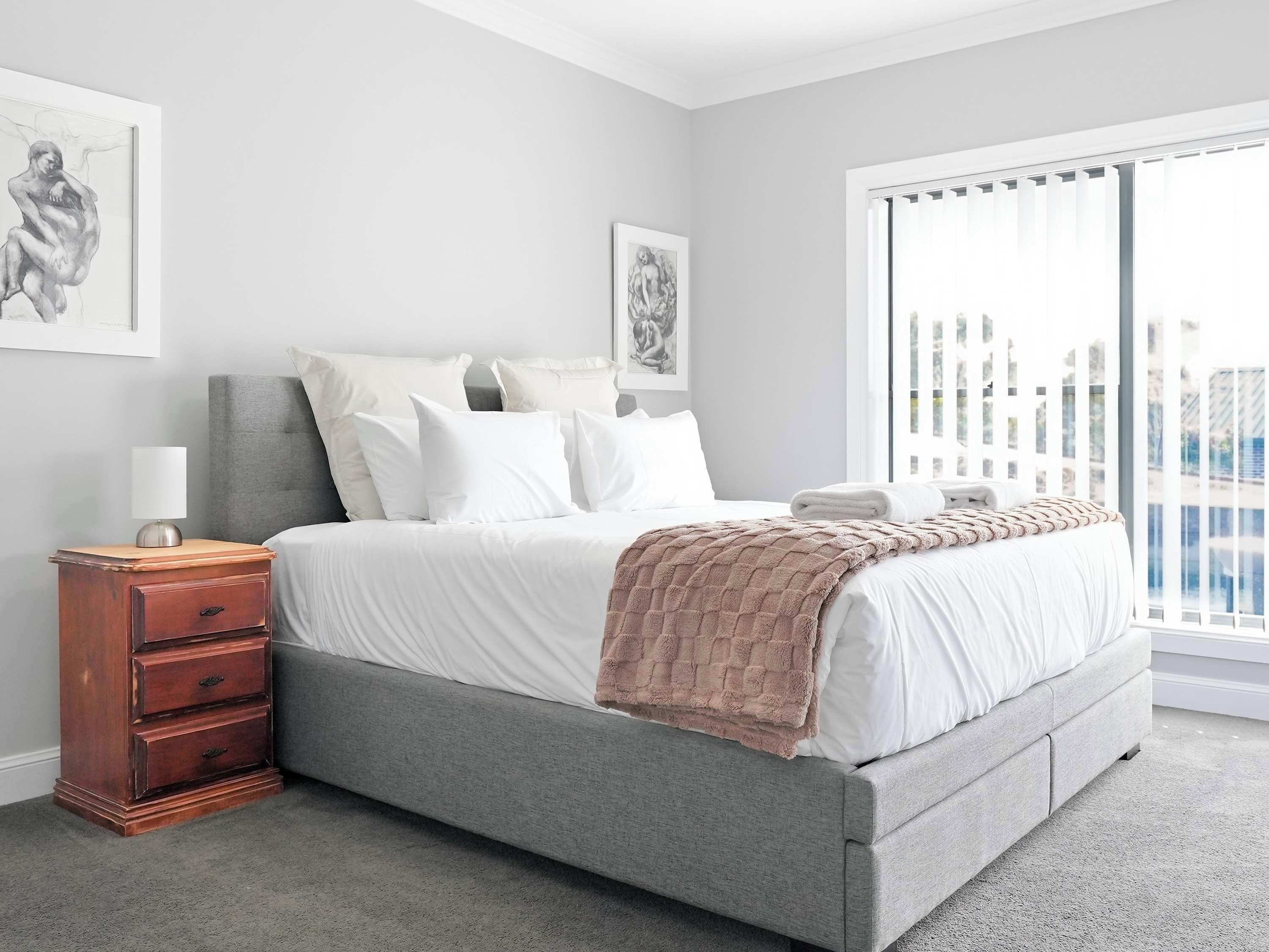 A bedroom with a bed, bedside table, and artwork on the wall.