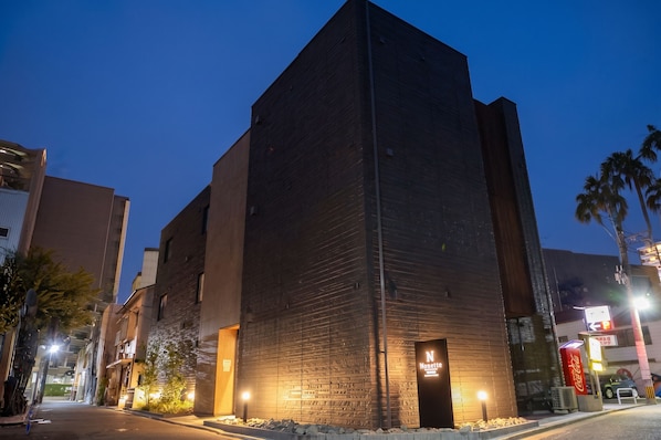 A tall, modern building with a flat roof and a large entrance.
