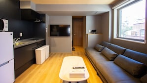 Un espacio habitable compacto con kitchenette, un sofá, un televisor y una ventana que ofrece vistas al exterior.