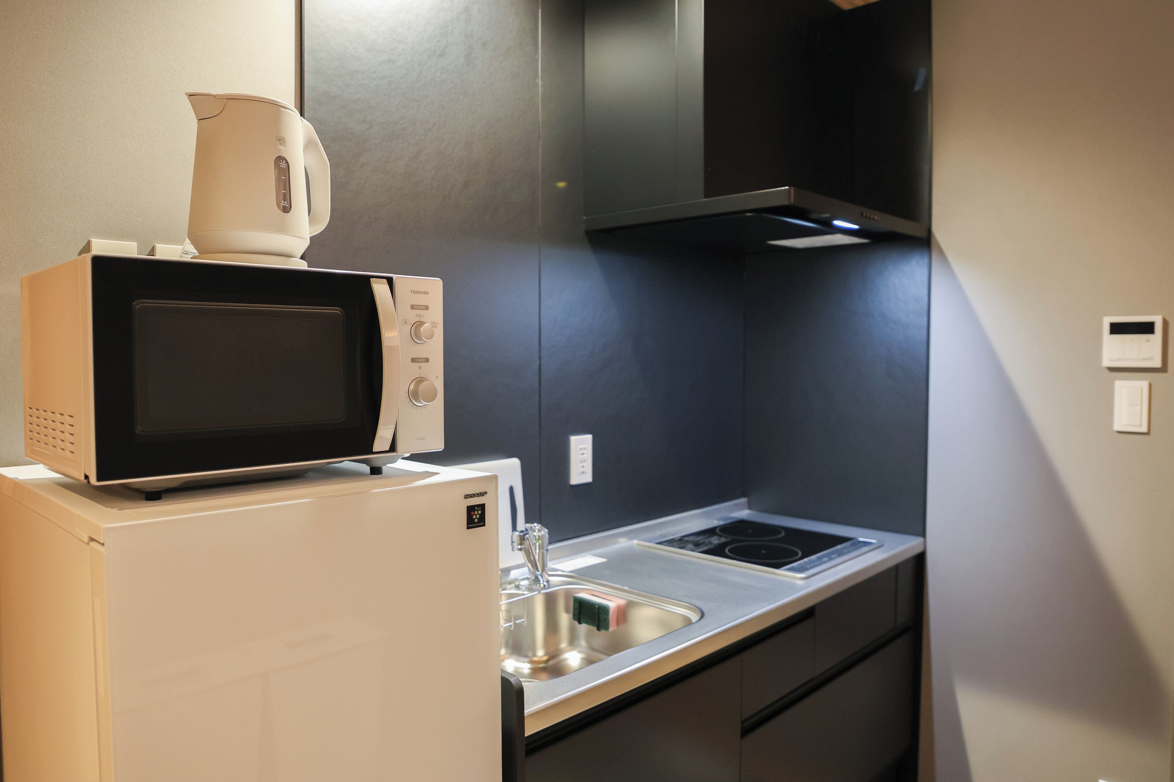 Una cocina compacta con un microondas sobre un refrigerador, una estufa y un lavaplatos.