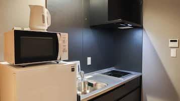 Una cocina compacta con un microondas sobre un refrigerador, una estufa y un lavaplatos.