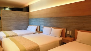 Habitación de hotel con dos camas, un cabecero de madera y una mesita de noche con una lámpara.