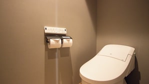 Un inodoro con dispensador de papel de pared y una pared lisa.