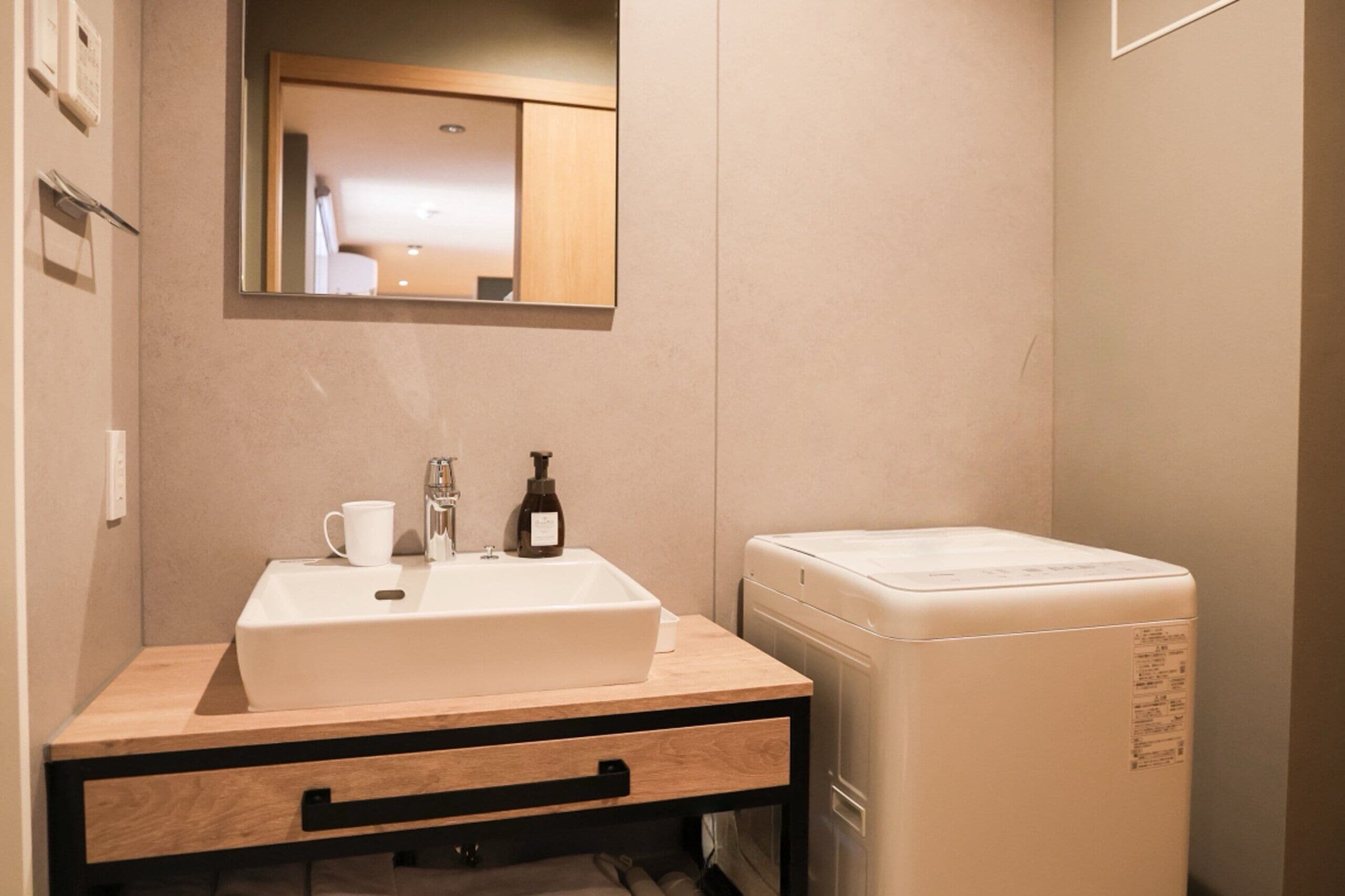 A bathroom with a white sink, a mirror, a white toilet, and a wooden vanity with a drawer.