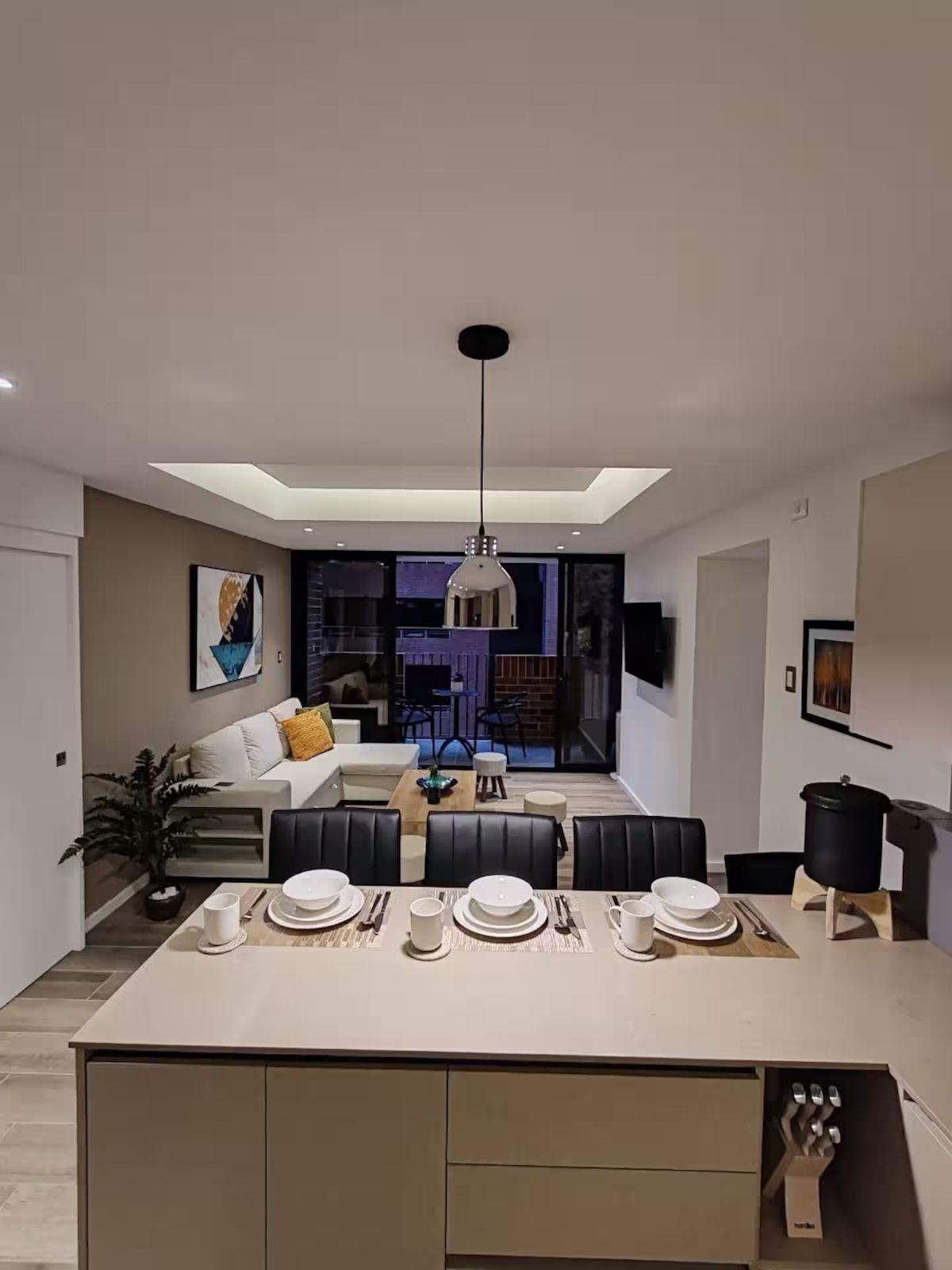 Une cuisine moderne dotée d’un îlot central, d’un coin repas et d’un espace de vie comprenant un canapé et une table basse.