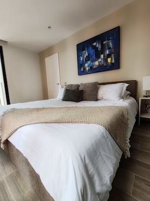 Ein Hotelzimmer mit einem großen Bett, einem Bild an der Wand und einem Nachttisch mit einer Lampe.