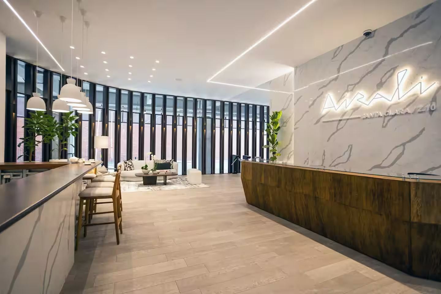 A modern reception area with a marble wall, a wooden reception desk, and a seating area with a sofa and chairs.