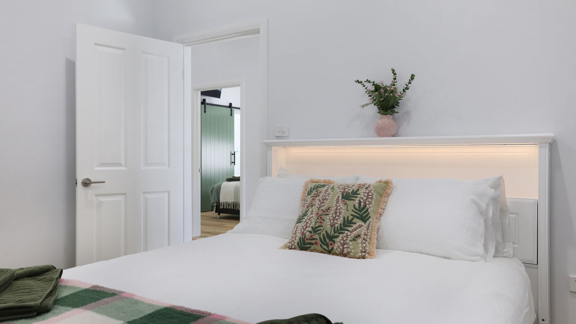 Ein Hotelzimmer mit einem Bett, einer T ür, einer Zimmerpflanze und Blick auf ein weiteres Zimmer.