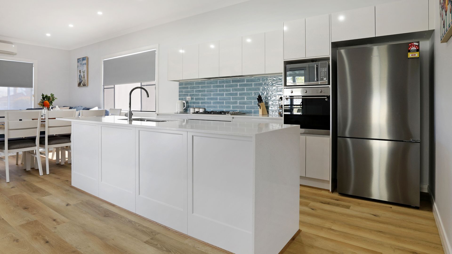 A modern kitchen with white cabinetry, a stainless steel refrigerator, and a tiled backsplash.