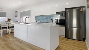 A modern kitchen with white cabinetry, a stainless steel refrigerator, and a tiled backsplash.