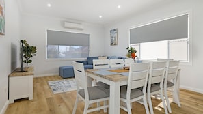 Un salon moderne avec un coin repas, comprenant un ensemble de canapés, une table basse et un téléviseur.