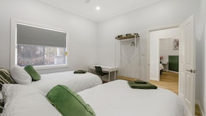 Une chambre avec deux lits, un bureau et une fenêtre.