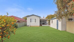 A residential property with a well-maintained lawn, a detached garage, and a small house with a porch.
