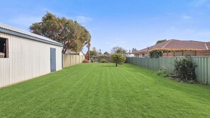 A well-maintained backyard with a lawn, a small tree, and a metal shed.