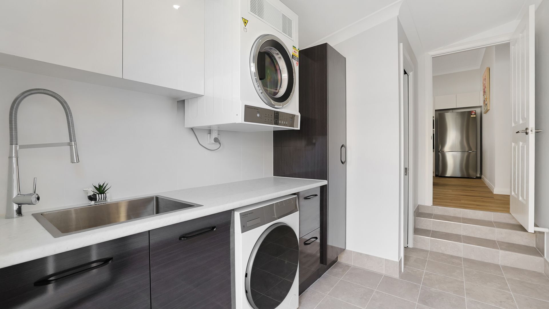 A modern kitchen with a built-in washing machine, a stainless steel sink, and a compact layout.