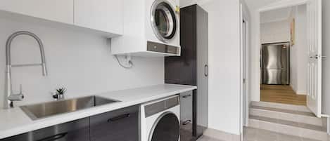 Una cocina moderna con lavadora integrada, un lavamanos de acero inoxidable y una distribución compacta.