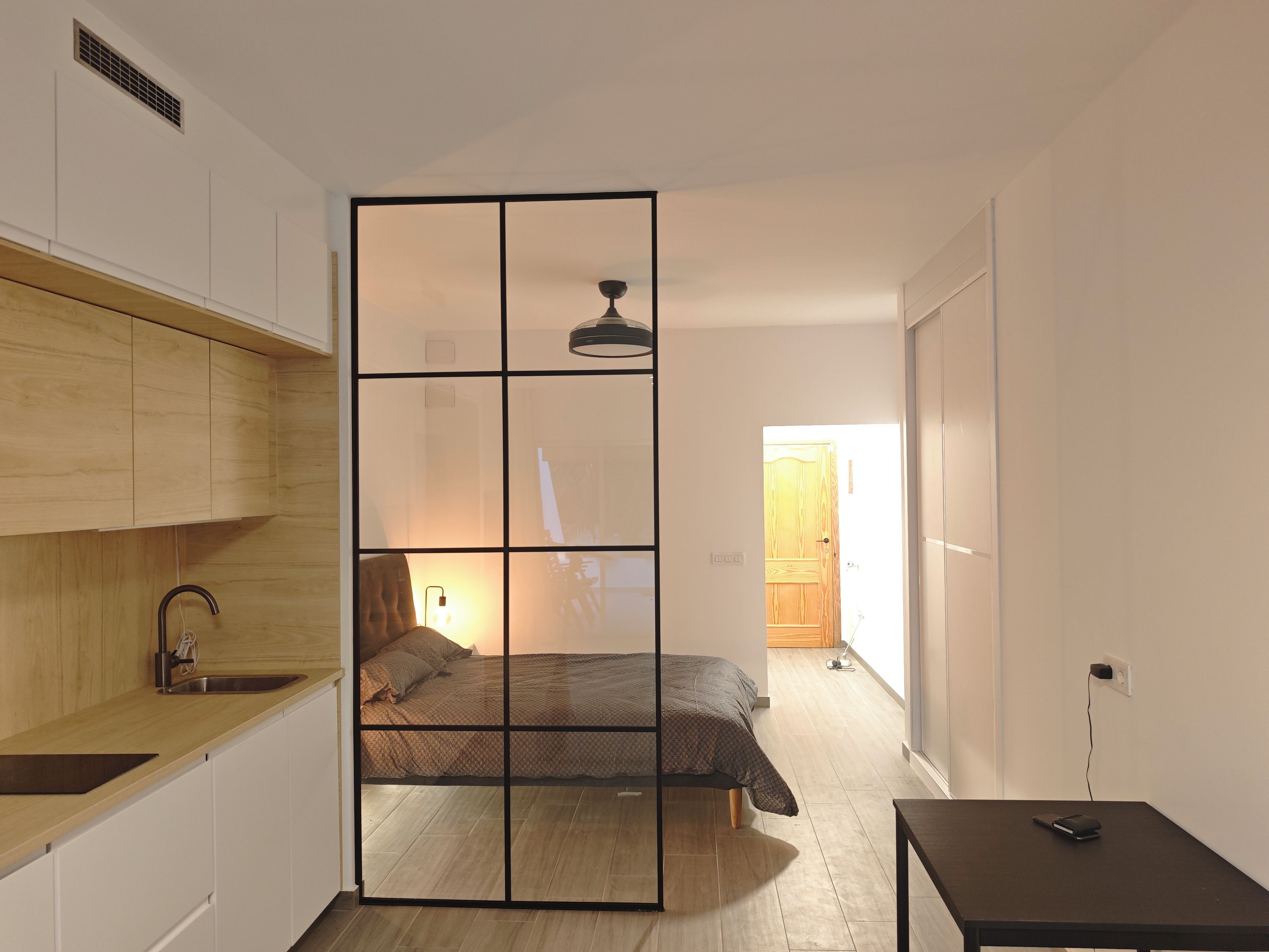 Une pièce compacte comprenant un coin cuisine, un lit et une petite table.