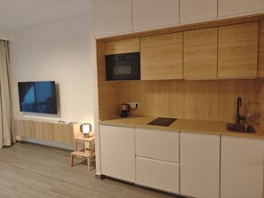 Una cocina moderna con armarios de madera, horno empotrado, pileta y un taburete de madera.