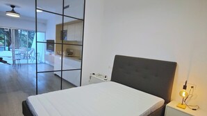 Quarto moderno com cama, mesa de cabeceira e luminária no teto.