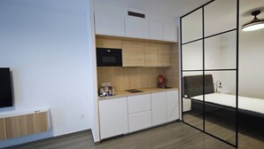 Quarto compacto com cozinha compacta, uma cama e uma janela grande.