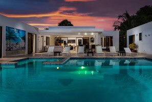 A swimming pool with lounge chairs, a dining area, and a sunset view. - Private, 5 BR, Lg Pool / Lawn, Fenced, Secluded (Sosua)