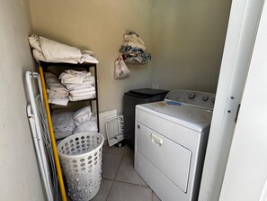 A laundry room with a washing machine, a drying rack, and a basket. - Private, 5 BR, Lg Pool / Lawn, Fenced, Secluded (Sosua)