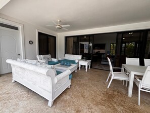 A covered patio area with white furniture, including sofas and a table, and a ceiling fan. - Private, 5 BR, Lg Pool / Lawn, Fenced, Secluded (Sosua)