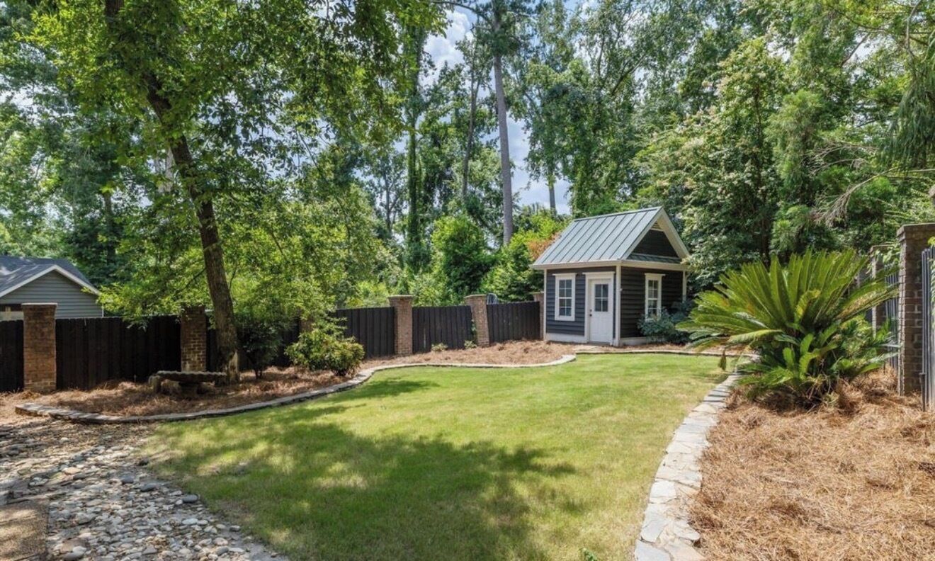 Une propriété résidentielle dotée d’une pelouse bien entretenue, d’un petit abri de jardin et d’un mur en briques.