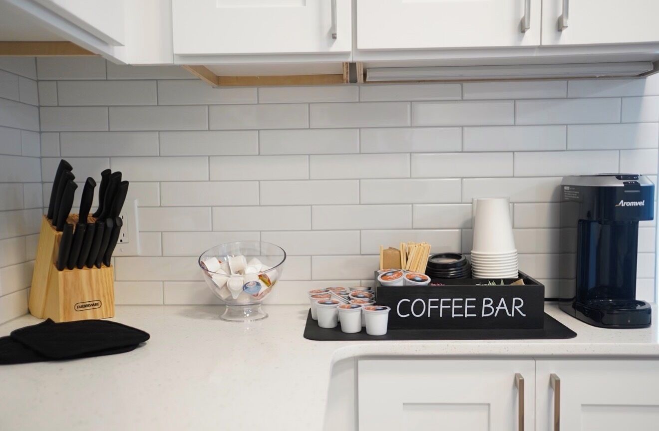 A kitchen with a coffee bar setup, including cups, a coffee maker, and a knife block.