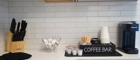 A kitchen with a coffee bar setup, including cups, a coffee maker, and a knife block.