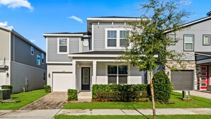 A residential building with a front entrance, a small tree, and a well-maintained lawn. - Brand New | 6BR Villa Pool & Spa,Loft near Disney 2380 (Kissimmee)