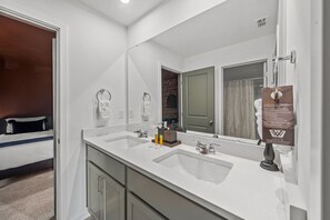A hotel bathroom with a double sink, a large mirror, and a towel policy sign. - Brand New | 6BR Villa Pool & Spa,Loft near Disney 2380 (Kissimmee)