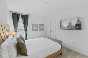 A bedroom with a bed, curtains, a door, and a wall-mounted Disney-themed picture. - Brand New | 6BR Villa Pool & Spa,Loft near Disney 2380 (Kissimmee)