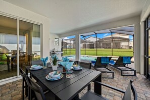 Eine Außenpatio mit Esstisch, Schwimmbad und Liegestühlen.
