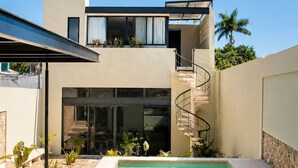 A modern two-story house with a swimming pool, a spiral staircase, and a covered patio area. - Casa Xunan (Mérida)