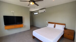 A bedroom with a bed, a TV mounted on the wall, a ceiling fan, and an air conditioning unit. - Casa Xunan (Mérida)