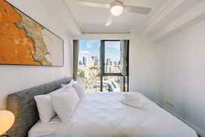 A hotel room with a bed, a ceiling fan, a large window with a city view, and a map on the wall. - One Bedroom Urban Solace Near CBD (Fortitude Valley)