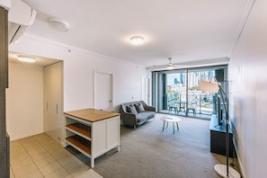 Eine moderne Wohnung mit Essbereich, einer Couch, einem kleinen Tisch und einem großen Fenster mit Blick auf die Stadt.