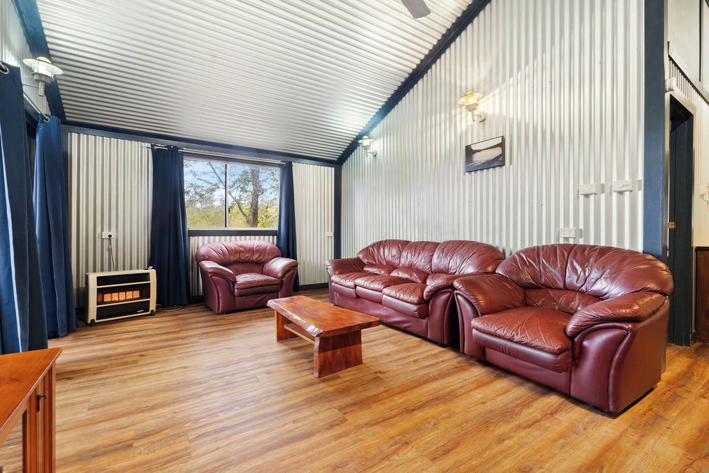 A room with a large leather sofa, a smaller sofa, and a wooden coffee table.
