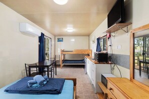 A compact room with a bunk bed, a desk with a chair, a small kitchenette, and a television. - Tiny Away Stay – Mann River (Jackadgery)