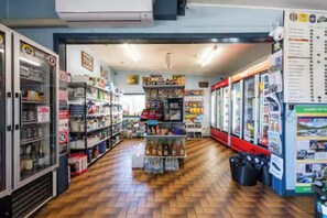 A store interior with shelves stocked with various products, a central display area, and a checkout counter.