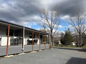 A building with a covered porch and a gravel driveway.