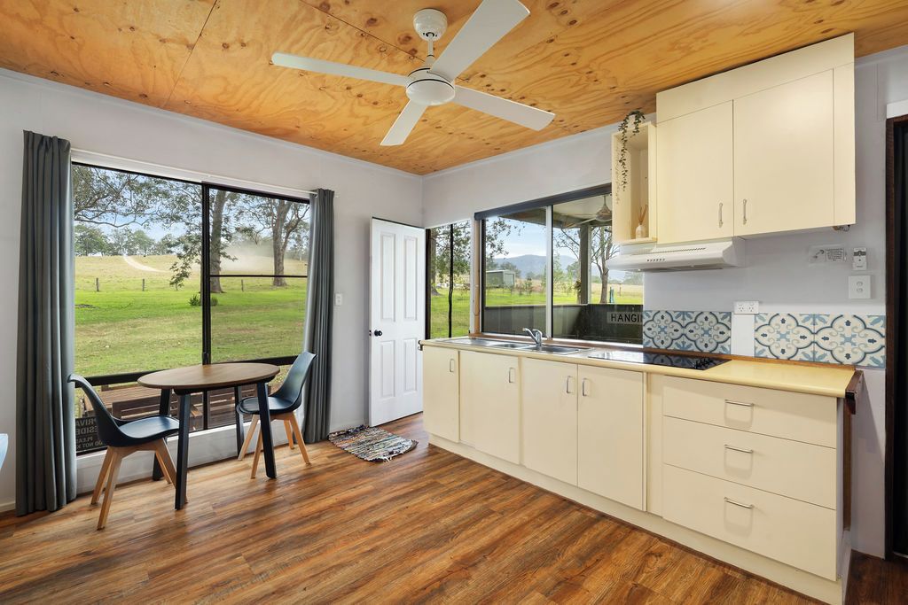 A kitchen with a view of the outdoors, wooden ceiling, and a dining area with chairs.