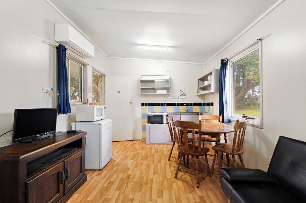 A compact kitchen with a dining area, a TV, and a small refrigerator.