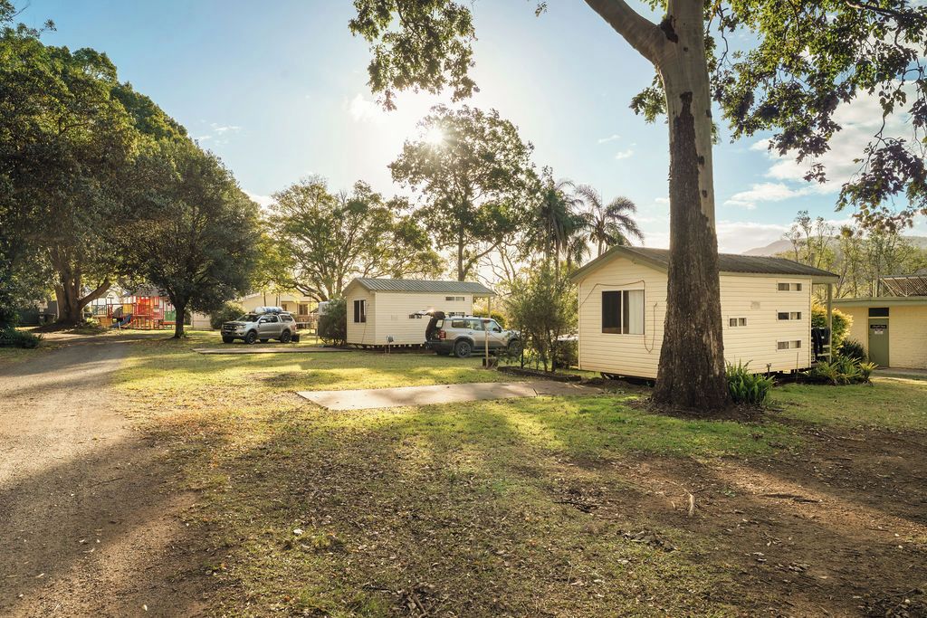 Zona residencial con casas móviles, entrada para vehículos y un árbol grande.